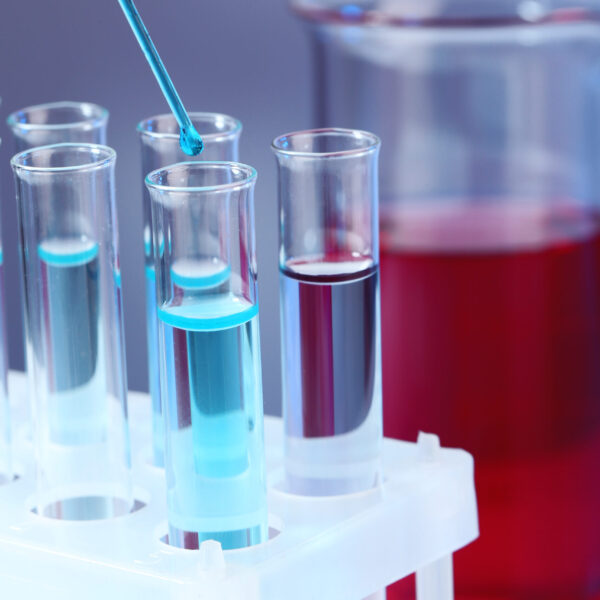 Test tubes with blue liquid and glass with red liquid on light background